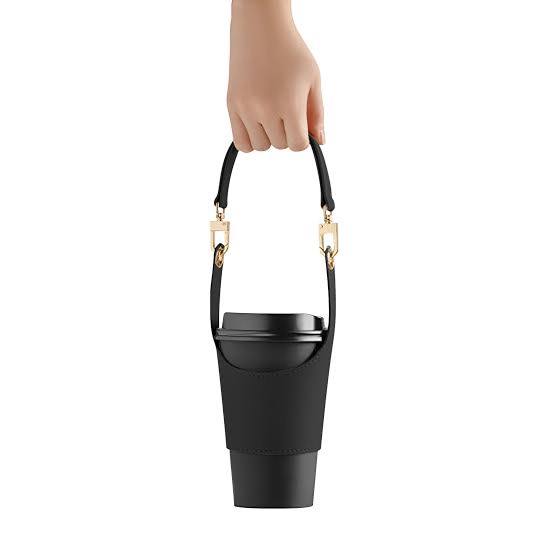Black coffee cup sleeve being carried by its detachable strap